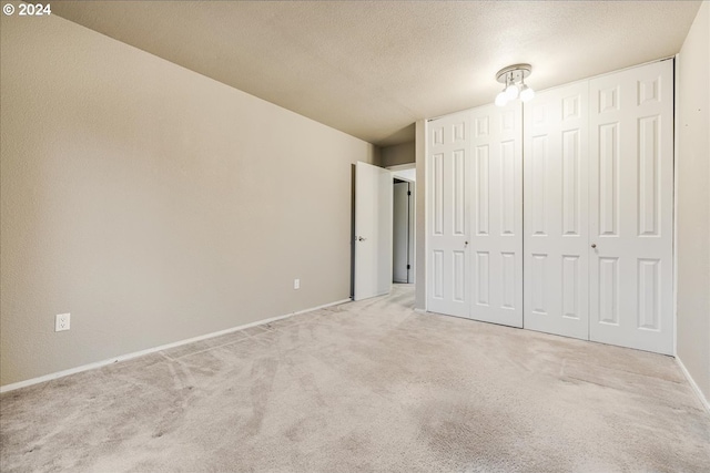 unfurnished bedroom with a closet, light carpet, and a textured ceiling