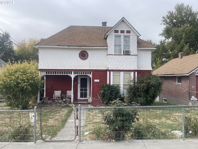 victorian home with a fenced front yard, a gate, a porch, and a shingled roof