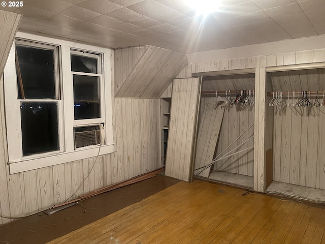 bonus room with hardwood / wood-style flooring, wooden walls, cooling unit, and lofted ceiling