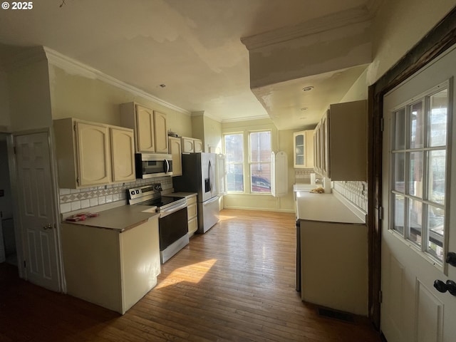 kitchen with stainless steel appliances, visible vents, ornamental molding, decorative backsplash, and wood-type flooring