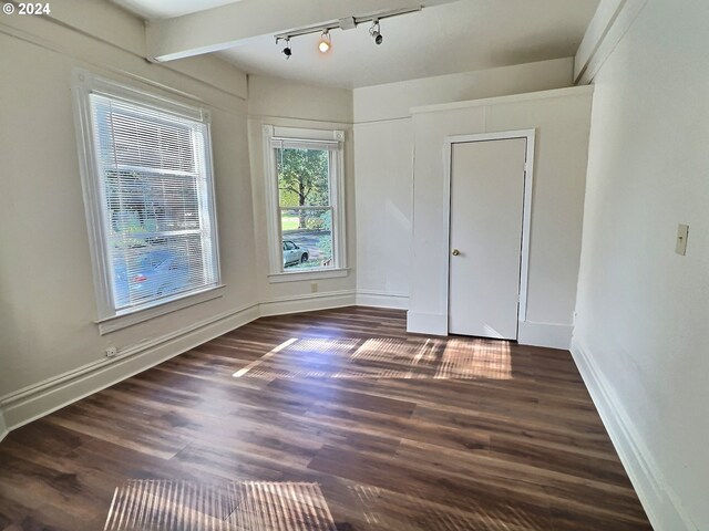 interior space featuring track lighting, beam ceiling, and dark hardwood / wood-style flooring