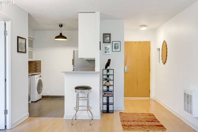 2020 SW Main St Unit 801, Portland, OR 97205 - kitchen with washer / clothes dryer, freestanding refrigerator, light wood finished floors, and backsplash