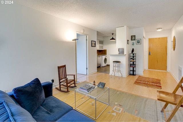 living room with light hardwood / wood-style floors, a textured ceiling, and washer / clothes dryer