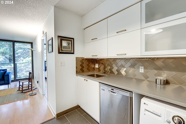 kitchen featuring white cabinetry, tasteful backsplash, stainless steel dishwasher, a textured ceiling, and washer / dryer