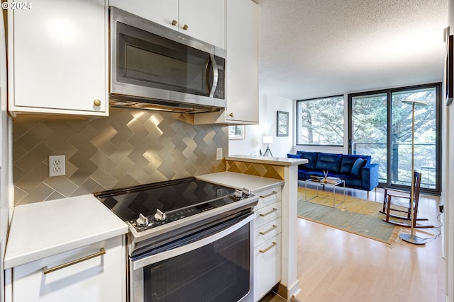 kitchen featuring white cabinetry, a textured ceiling, appliances with stainless steel finishes, and light hardwood / wood-style flooring