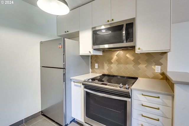 kitchen with white cabinets, backsplash, light tile patterned floors, and stainless steel appliances