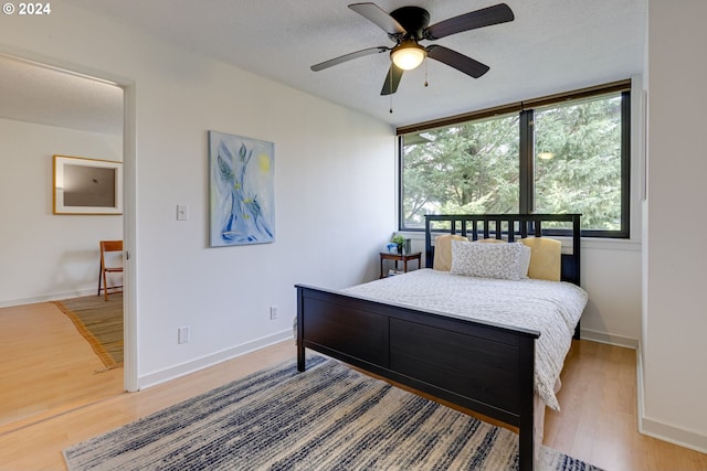 bedroom featuring hardwood / wood-style floors, ceiling fan, and a textured ceiling