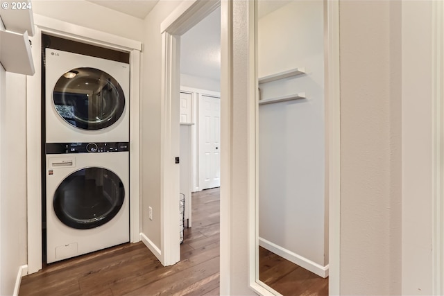 laundry room with stacked washing maching and dryer and dark hardwood / wood-style floors