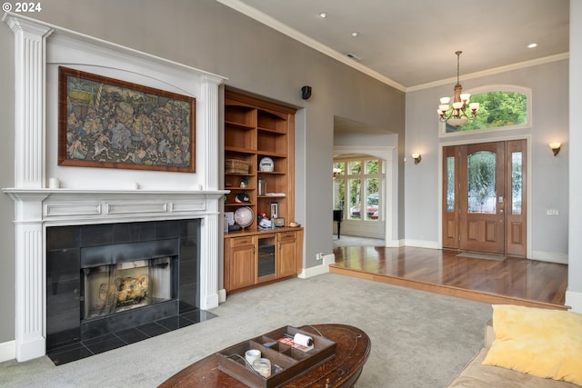 living room with a chandelier, light carpet, a tiled fireplace, and crown molding