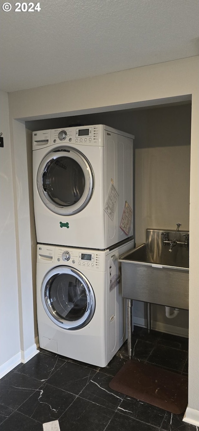 washroom featuring dark tile patterned flooring and stacked washing maching and dryer