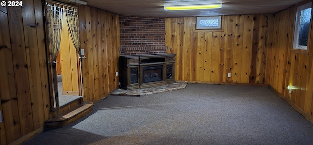 interior space featuring wood walls, a large fireplace, brick wall, and carpet flooring