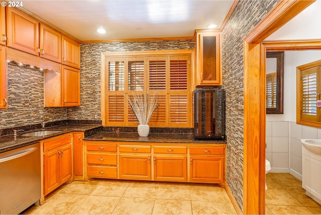 kitchen with dishwasher, dark stone counters, sink, and ornamental molding