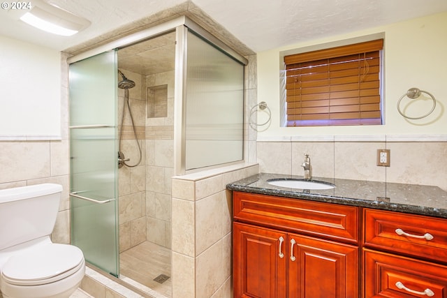 bathroom with vanity, tile walls, toilet, a shower with door, and decorative backsplash