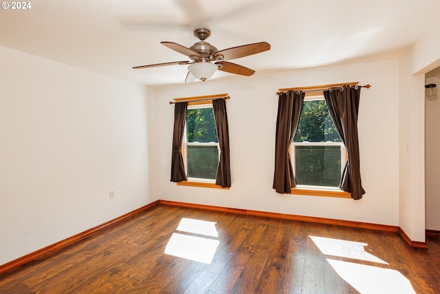 empty room with a healthy amount of sunlight, dark wood-type flooring, and ceiling fan