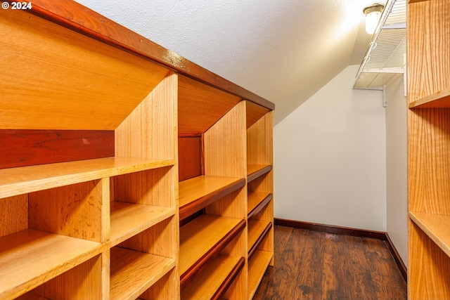 walk in closet with vaulted ceiling and dark hardwood / wood-style floors