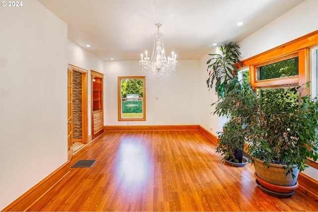 spare room featuring an inviting chandelier and light wood-type flooring