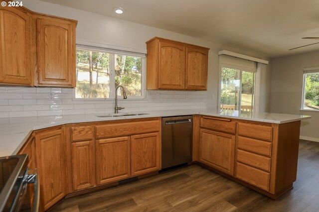 kitchen featuring backsplash, dishwasher, sink, kitchen peninsula, and dark wood-type flooring