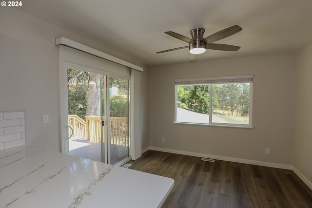 unfurnished bedroom featuring baseboards, multiple windows, dark wood-style floors, and access to exterior