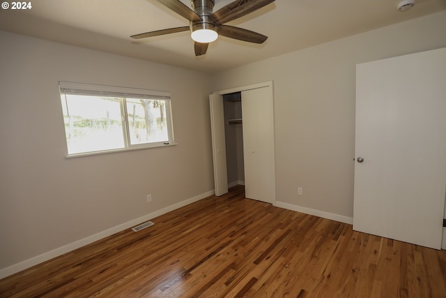 unfurnished bedroom with baseboards, visible vents, ceiling fan, wood finished floors, and a closet