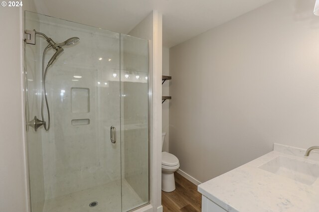 bathroom with hardwood / wood-style floors, toilet, an enclosed shower, and vanity