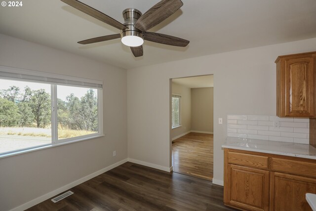 unfurnished dining area with ceiling fan and dark wood-type flooring