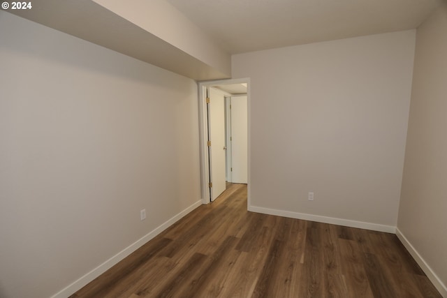 empty room featuring baseboards and dark wood-style flooring