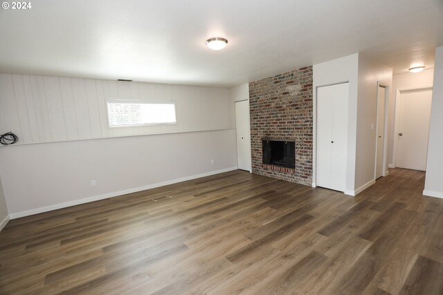 unfurnished living room featuring a brick fireplace, brick wall, and wood-type flooring