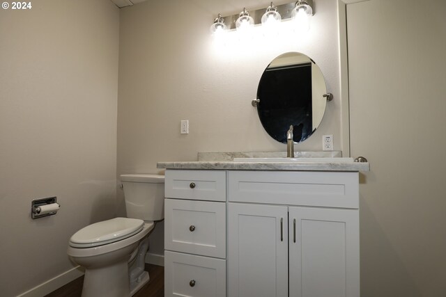 bathroom with hardwood / wood-style flooring, toilet, and vanity