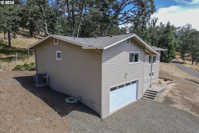 view of side of home featuring a garage and cooling unit