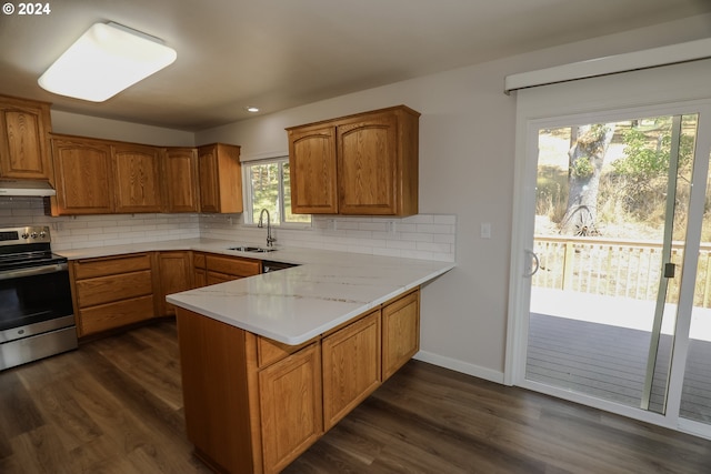 kitchen with brown cabinetry, dark wood-style floors, stainless steel electric stove, under cabinet range hood, and a sink