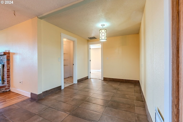 unfurnished room featuring a fireplace, dark tile patterned floors, and a textured ceiling