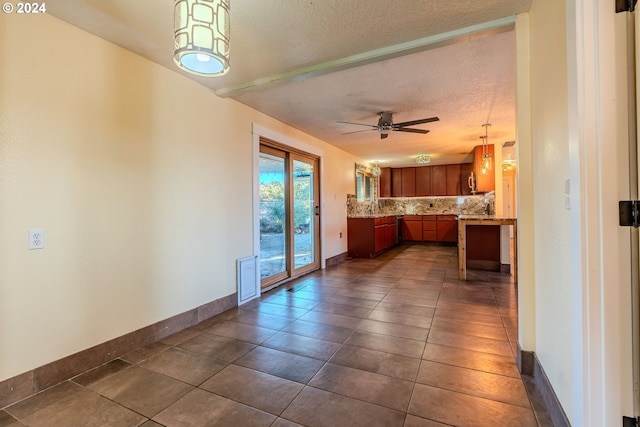 kitchen featuring a textured ceiling, backsplash, dark tile patterned floors, and ceiling fan