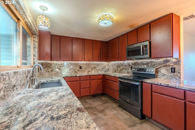 kitchen featuring backsplash, a textured ceiling, stainless steel appliances, sink, and hanging light fixtures