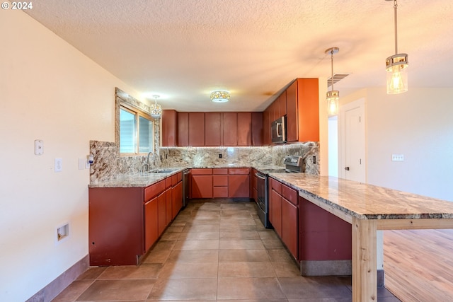 kitchen with kitchen peninsula, sink, stainless steel appliances, and decorative light fixtures