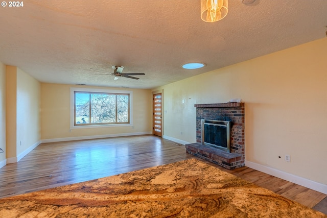 unfurnished living room featuring ceiling fan, a fireplace, a textured ceiling, and hardwood / wood-style flooring