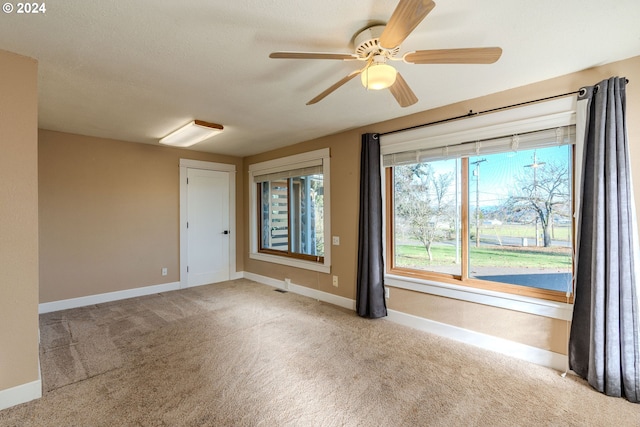 spare room with ceiling fan and light carpet