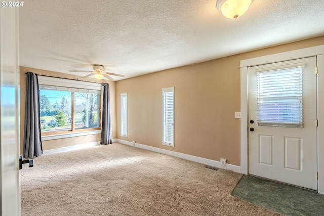 entrance foyer featuring carpet flooring, a textured ceiling, a wealth of natural light, and ceiling fan