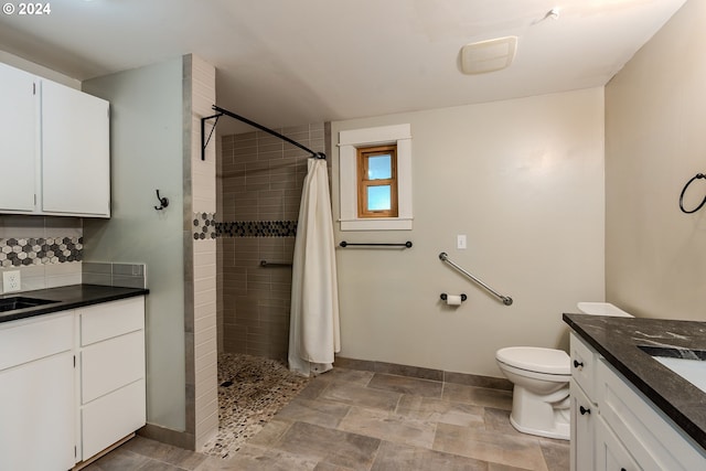 bathroom with a shower with shower curtain, vanity, toilet, and decorative backsplash