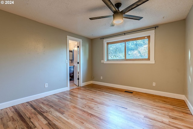 unfurnished bedroom featuring a textured ceiling, light hardwood / wood-style floors, ceiling fan, and connected bathroom