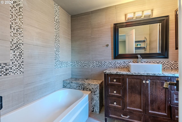 bathroom featuring vanity, a tub to relax in, tile walls, and tasteful backsplash