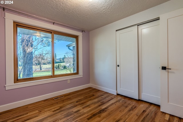 unfurnished bedroom with a closet, wood-type flooring, and a textured ceiling