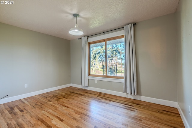 unfurnished room with a textured ceiling and light wood-type flooring