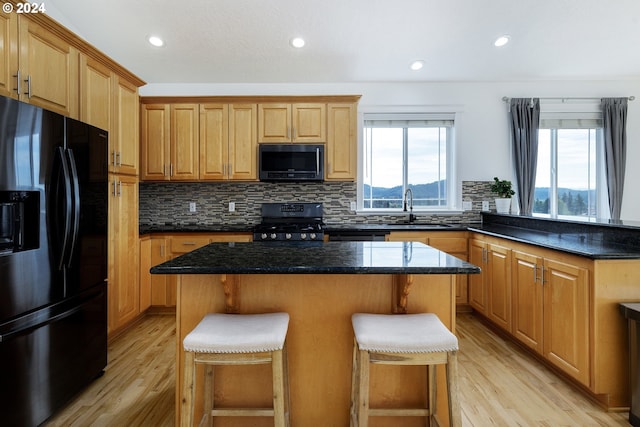 kitchen with black appliances, a center island, light wood-type flooring, and sink