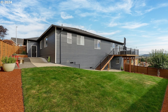 back of house featuring a lawn, a patio, and a wooden deck