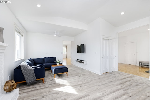 living room featuring light wood-type flooring, a brick fireplace, ceiling fan, and lofted ceiling