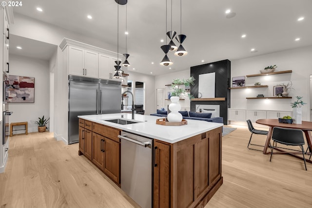 kitchen featuring sink, hanging light fixtures, a center island with sink, white cabinets, and appliances with stainless steel finishes