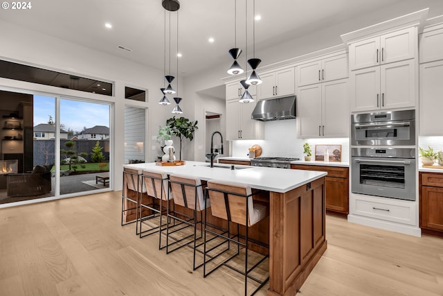 kitchen with white cabinetry, sink, an island with sink, and hanging light fixtures