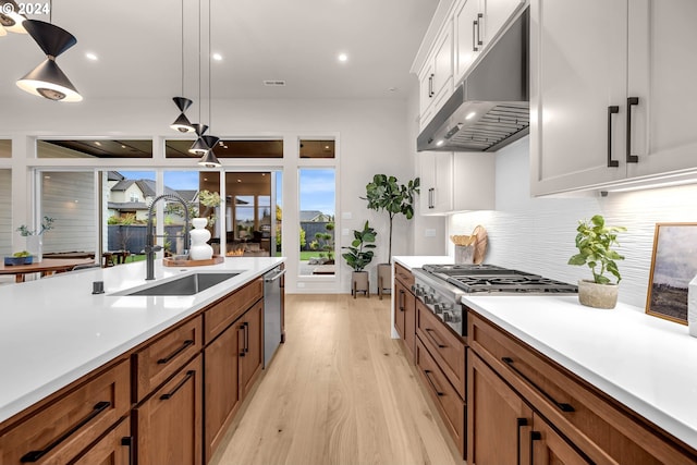 kitchen featuring white cabinets, sink, light hardwood / wood-style flooring, decorative backsplash, and decorative light fixtures