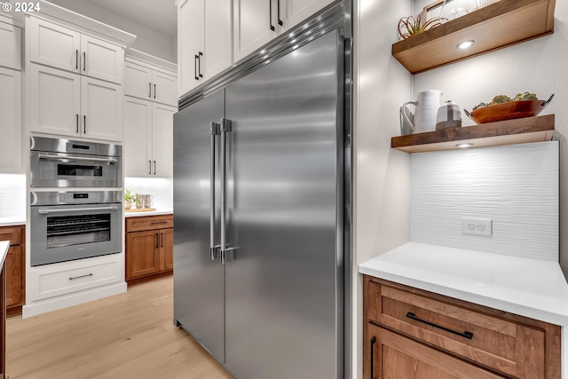 kitchen with white cabinets, stainless steel appliances, and light hardwood / wood-style floors