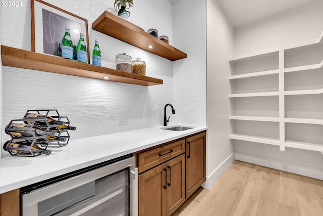 bar with sink, beverage cooler, and light hardwood / wood-style flooring